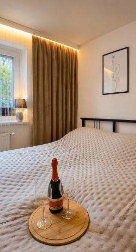 a bottle of wine and two glasses on a bed at Bytom Apartament 24H in Bytom