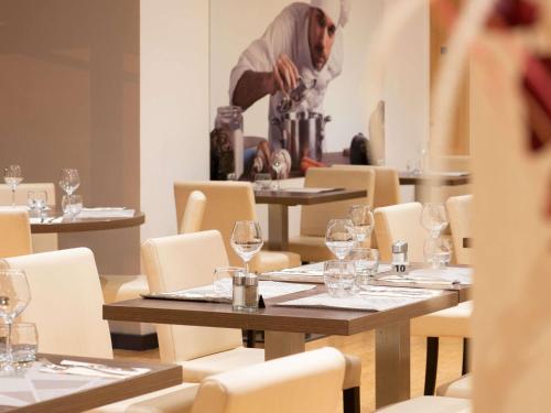 a man standing in a dining room with tables with wine glasses at ibis budget Lyon Est Chaponnay in Chaponnay