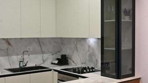 a kitchen with white cabinets and a sink at Lazari S Apartments in Himare