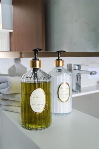 two bottles of soap sitting on a bathroom sink at The Alpfine Hotel in Ankara