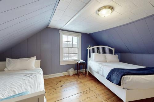 a bedroom with two beds and a blue wall at Green Door Cottage in Weston