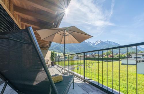 a balcony with a chair and an umbrella at Apart Dorhoam in Umhausen