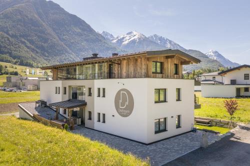 an image of a house with mountains in the background at Apart Dorhoam in Umhausen