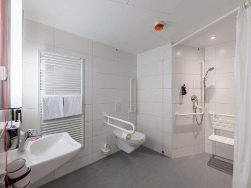 a white bathroom with a toilet and a sink at Ibis Berlin Hauptbahnhof in Berlin
