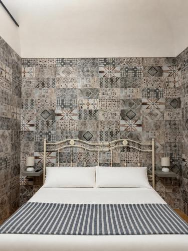 a bedroom with a bed and a wall with tiles at Lauro Apartment in Meta