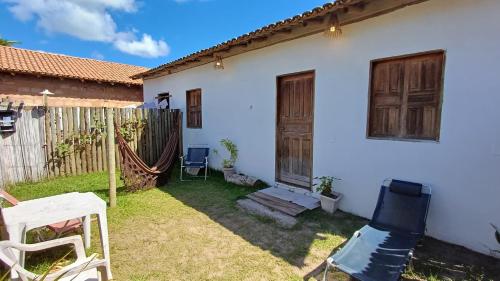 a white house with a yard with chairs and a fence at Casa Mar in Caraíva