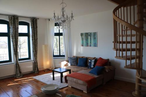 a living room with a couch and a chandelier at Gutshaus Alt Vorwerk in Boddin