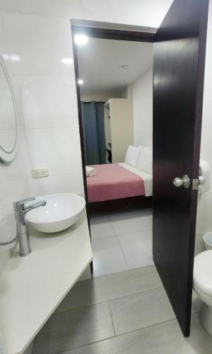 a bathroom with a sink and a toilet and a bed at Hotel Bocagrande Cartagena in Cartagena de Indias
