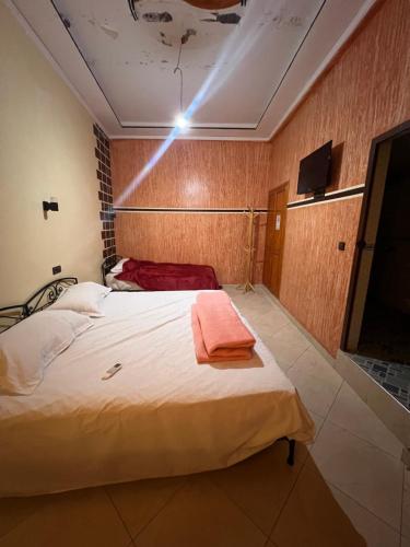 a bedroom with a bed and a tv on the ceiling at Merzouga Roms in Merzouga