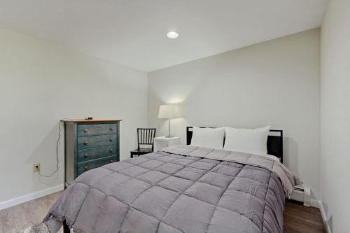 a white bedroom with a large bed and a dresser at Frozen Jamaica in Jamaica