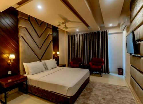 a bedroom with a bed and a desk and a television at Galaxy Family Hotel Karachi Airport in Karachi