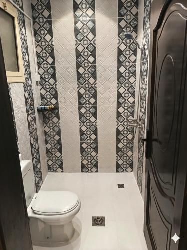 a bathroom with a toilet and a tile wall at رفاه in Medina