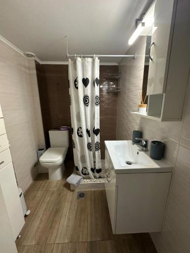 a bathroom with a toilet and a shower curtain at Paul House in Metamorfosi