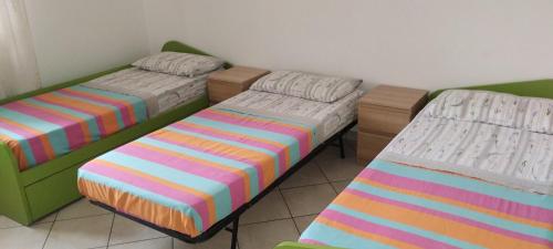 a room with three beds with colorful striped sheets at Villa Pina in Vico Equense