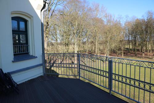 a balcony of a house with a fence and trees at Gutshaus Alt Vorwerk in Boddin
