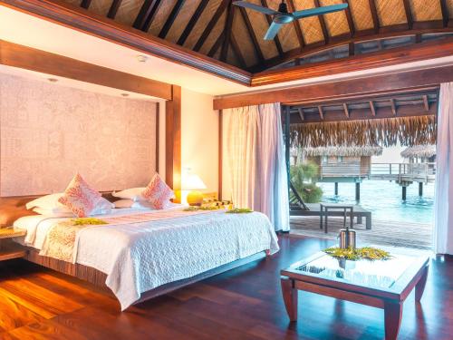 a bedroom with a large bed and a large window at Manava Beach Resort & Spa Moorea in Maharepa
