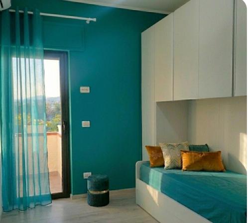 a blue bedroom with a bed and a window at ANAMI' Suite Apartament in Bovalino Marina