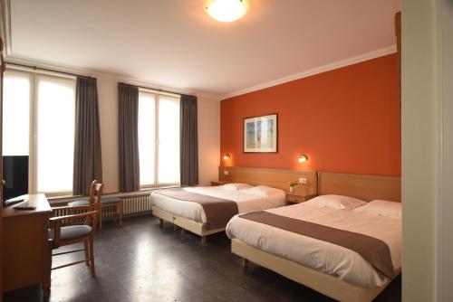 2 Betten in einem Hotelzimmer mit orangefarbenen Wänden in der Unterkunft Hotel Sabot D'Or in Blankenberge