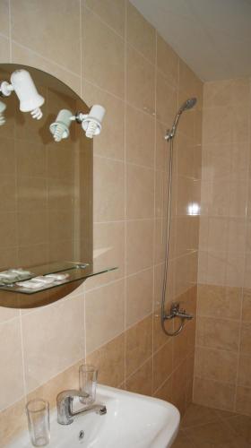 a bathroom with a shower with a sink and a mirror at Guest House Garbevi in Dobrinishte