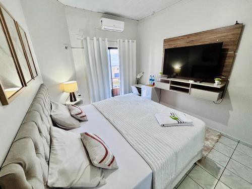 a bedroom with a large bed and a television at Hospedagem Domiciliar em Lucas do Rio Verde in Lucas do Rio Verde