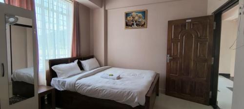a bedroom with a bed and a window and a door at Townhouse Mylliem Formerly Infinity Bed & Breakfast in Shillong