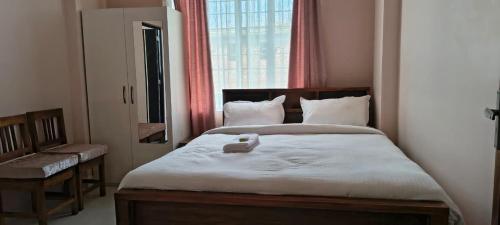 a bedroom with a large bed with a window at Townhouse Mylliem Formerly Infinity Bed & Breakfast in Shillong
