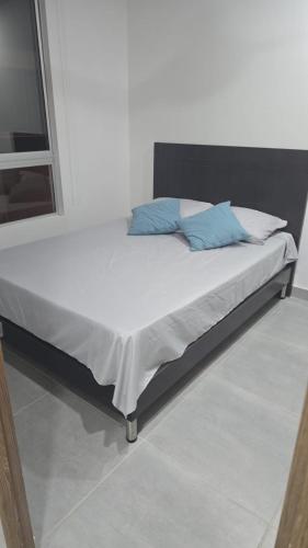 a bed with two blue pillows on top of it at Espectacular casa, piscina privada- Ricaurte in Ricaurte