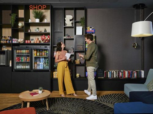 a man and a woman standing at a counter in a store at Aparthotel Adagio Access La Défense Puteaux in Puteaux