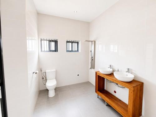 a white bathroom with a toilet and a sink at villa face à la mer in Cotonou