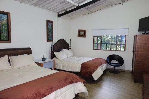 a bedroom with two beds and a flat screen tv at Finca eventos Dalubsu in Silvania