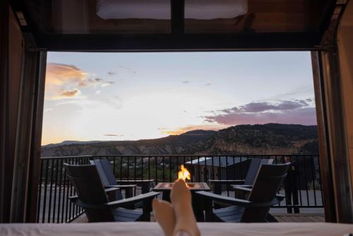 a room with a view of a table and chairs with a fire at Iron Cliff in Orderville