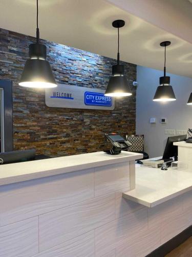 a lobby with a reception counter with three lights at City Express by Marriott Spring North Houston in Spring