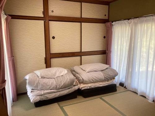 two beds sitting in a room with a window at ライダーハウスみかさんち in Marugame