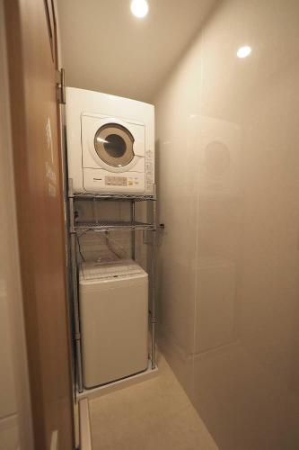 a small bathroom with a microwave and a washer at ライダーハウスみかさんち in Marugame