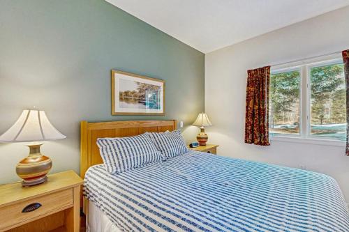 a bedroom with a bed with a blue comforter and two windows at Eagles Unit #2 in Jeffersonville