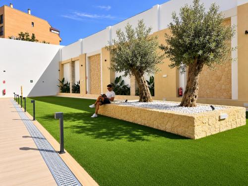 a man sitting on a bench in a yard with trees at Maritime Coliving Valencia in Valencia