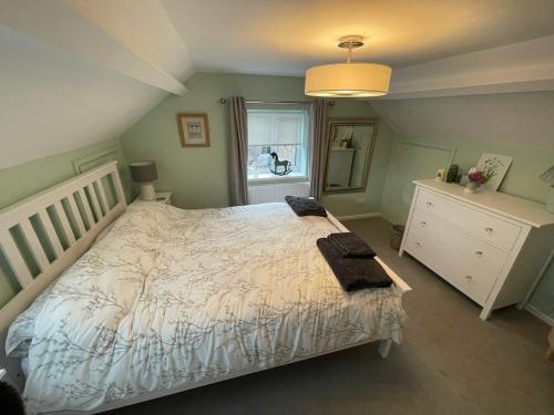 a bedroom with a bed with a white comforter and a window at Brook Lodge, One bed house in AONB Dorset with swimming pool in Iwerne Minster