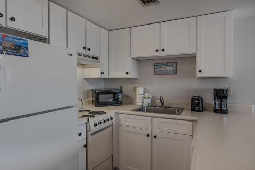 a kitchen with white cabinets and a stove and a sink at The Palace 505 in Myrtle Beach