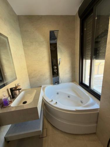 a bathroom with a large tub and a sink at Royal Pearl Villa 1 in Sowayma