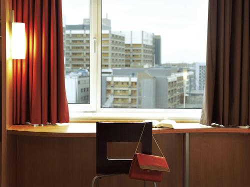 a desk with a chair in front of a window at ibis Arapiraca in Arapiraca