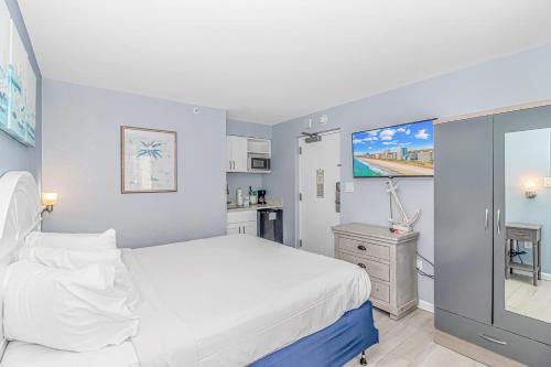 a bedroom with a white bed and a kitchen at Oceanview Studio at Boardwalk Resort 440 in Myrtle Beach