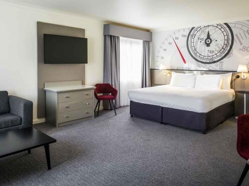 a hotel room with a bed and a clock on the wall at Mercure Dartford Brands Hatch Hotel & Spa in Dartford
