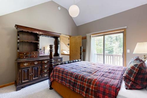 a bedroom with a bed with a dresser and a mirror at Chalet Gibby in Killington