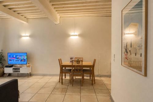 a dining room with a table and chairs and a tv at Bright Nîmes Center Flat with Terrace in Nîmes