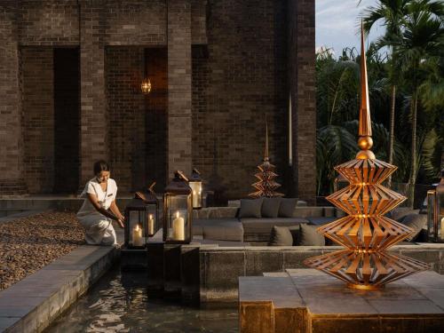a woman sitting in front of a building with a fountain at Avista Hideaway Phuket Patong - MGallery in Patong Beach