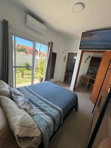 a bedroom with a bed and a large window at Piscina Aquecida Quartos com Ar cond 700m Praia in Peruíbe