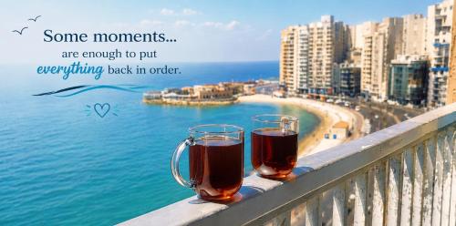 two glasses of beer sitting on a balcony overlooking the ocean at Nour 1 Sea View Apartment in Alexandria