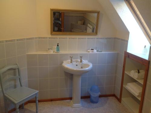 a bathroom with a sink and a mirror and a chair at Lochview Guesthouse in Contin