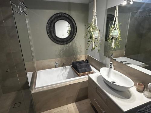 a bathroom with a tub and a sink and a mirror at Rye Hide Out - Rye beach retreat in Rye