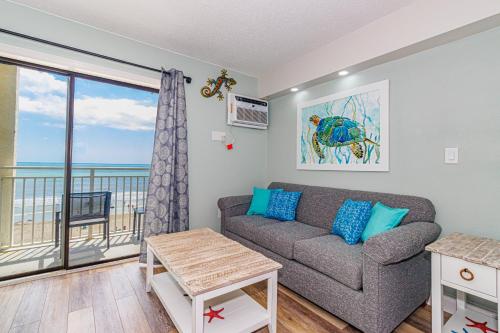 a living room with a couch and a balcony at Ocean Front Condo Sea Mist 20509 in Myrtle Beach